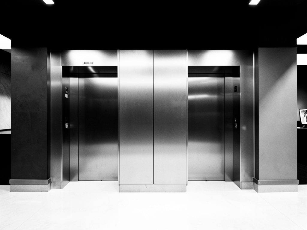 Infotraq Facilities, Elevators: a pair of steel elevator doors in a lobby, in black and white