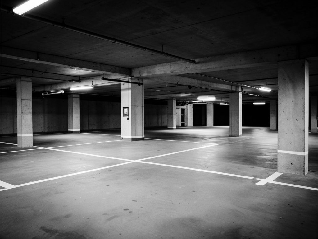 Infotraq Facilities, Parking: an empty underground car park with marked spaces, in black and white