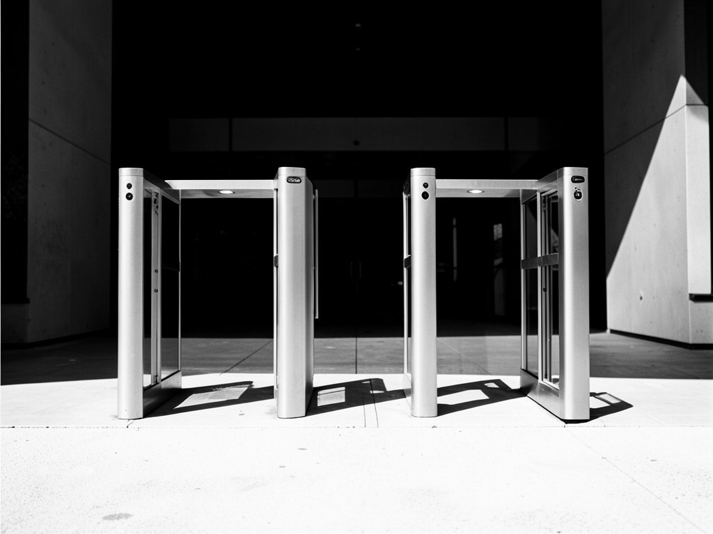 Infotraq Visitors: security entry gates at a building entrance, in black and white